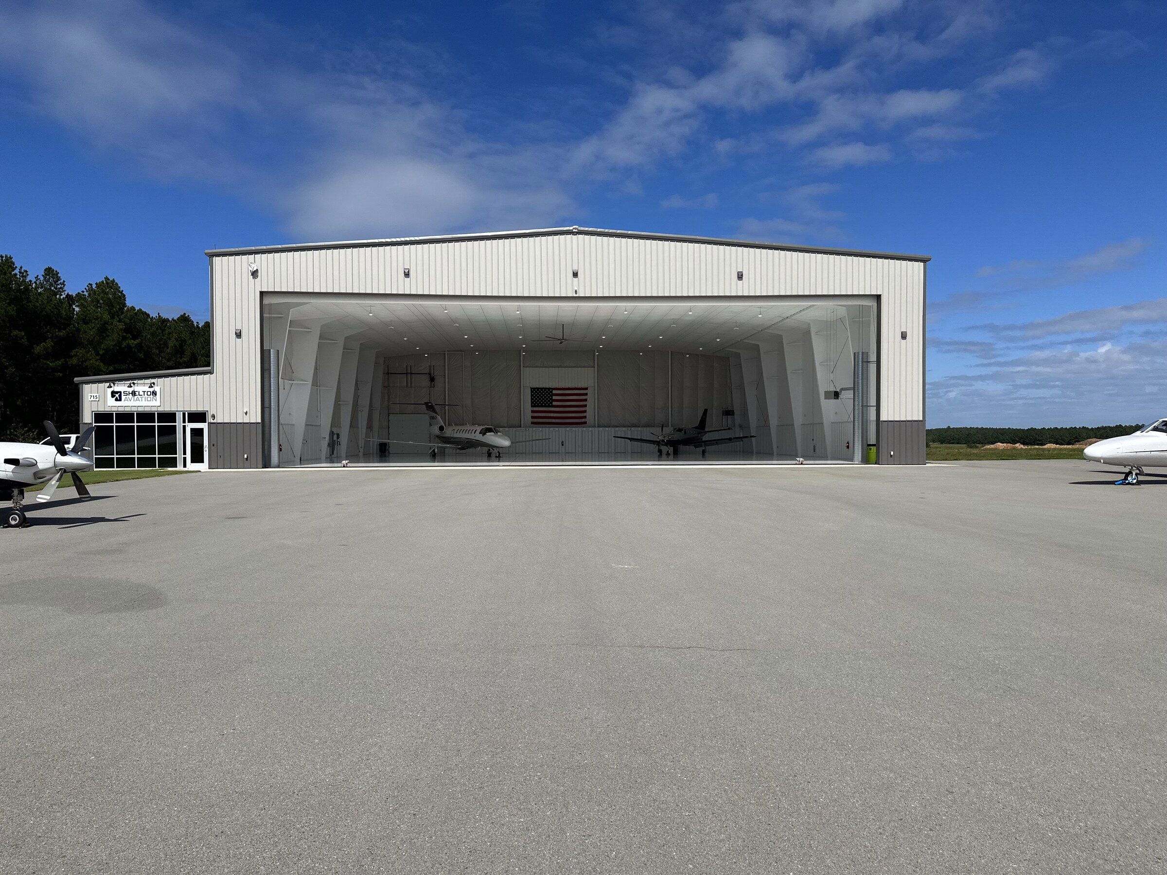 The hangar seen straight-on from the ramp with the door open and aircraft inside